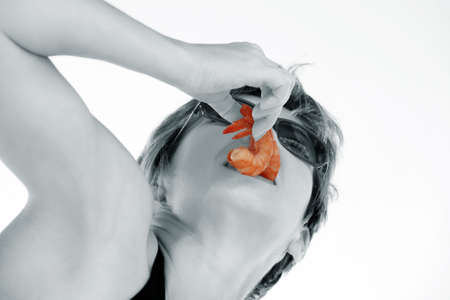 Woman is holding two shrimp in her mouthの写真素材