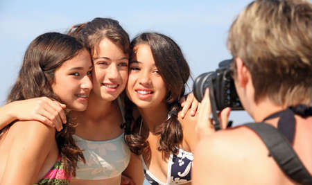 Mother is taking pictures of three teenage girlsの写真素材