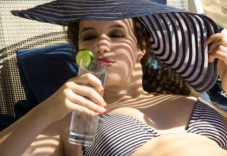 Gorgeous teen girl drinking water on the beachの写真素材
