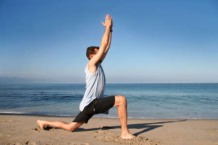 Man doing yoga exercise on the beach