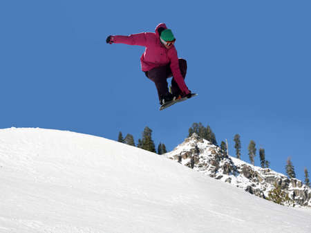 Teenager jumping high on a snowboard at the ski resort