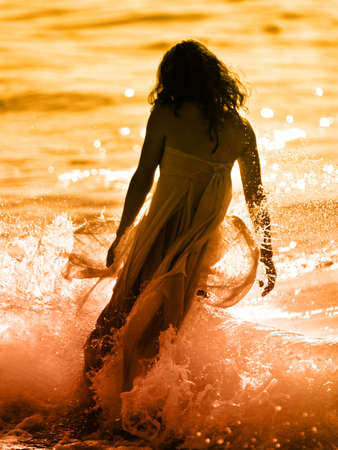 Woman on the beach at sunsetの写真素材