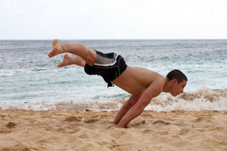 Young man doing handstand on the beachの写真素材