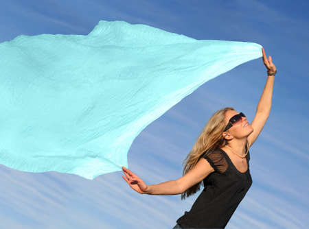 A young blond woman running with a scarfの写真素材