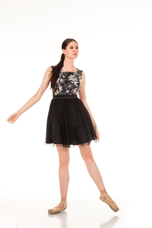 Beautiful young ballerina, isolated on white background. In pointes and black ballet tutu. Sits on the twine, shows different poses. graceful brunette with long hairの写真素材