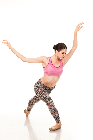 Beautiful slender ballerina in pointe shoes, posing in dance. Isolated photo on a white background. Shows different poses in ballet. Dressed in tights and pink topの写真素材