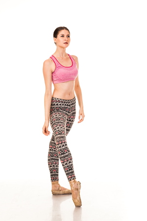 Beautiful slender ballerina in pointe shoes, posing in dance. Isolated photo on a white background. Shows different poses in ballet. Dressed in tights and pink topの写真素材