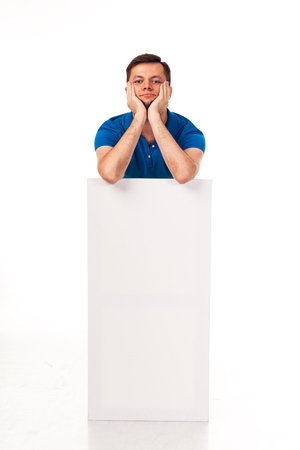 A guy with a beard posing with a white sign. Shows different emotions. Isolated on a white background. In a gray trousers and a blue T-shirt. For advertising, logo, business cards, contact phones, etcの写真素材