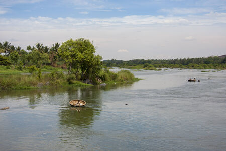 Round coracle boats rowing on wide Cauveri river in Karnataka, Indiaのeditorial素材