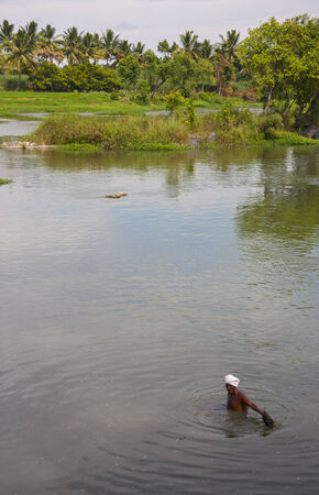 Indian fisherman standing in river throwing out fishing netのeditorial素材
