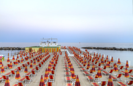 Beach chairs and umbrellas in rows converging into coastal horizon at beach terrace in  San Remo, Italy, Europe in twilight hourのeditorial素材