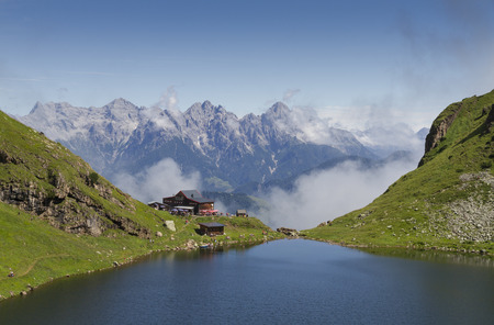 Mountain lodge Wildseeloderhaus majestically set at the edge of the Karsee mountain lake with view on Kitzbuheler Alps. Outdoor tourists are hiking along the lake.のeditorial素材