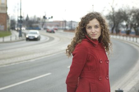 Teenage girl in Poland, portrait. Young girl with curly hairs wearing red coat, posing in Wroclaw city. の写真素材
