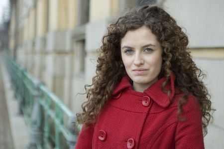 Teenage girl in Poland, portrait. Young girl with curly hairs wearing red coat, posing in Wroclaw city. の写真素材