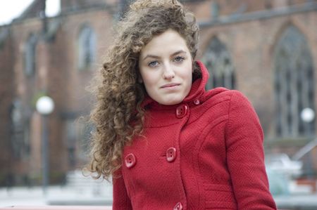Teenage girl in Poland, portrait. Young girl with curly hairs wearing red coat, posing in Wroclaw city. の写真素材