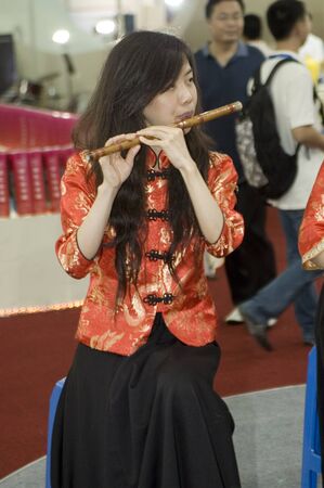 CHINA, GUANGDONG, SHENZHEN - MAY 16, 2009: China International Cultural Industries Fair: young, pretty Asian musician, using traditional Chinese instrument.のeditorial素材