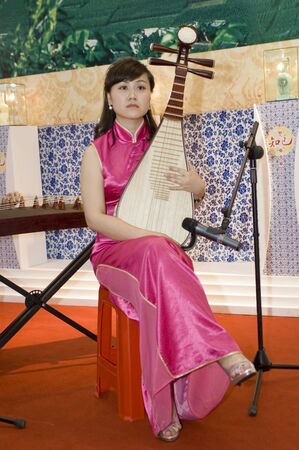CHINA, GUANGDONG, SHENZHEN - MAY 16, 2009: China International Cultural Industries Fair: young, pretty Asian musician, using traditional Chinese instrument.のeditorial素材