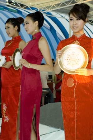 CHINA, GUANGDONG, SHENZHEN - MAY 16, 2009: China Cultural Industries Fair: beautiful Chinese hostess present Chinese porcelain, ceramic tea sets, vases, pots, plates.のeditorial素材