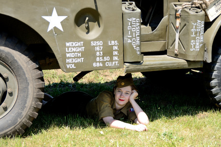 WROCLAW, POLAND - JUNE 3: Reconstruction groups rally. Militarians fan gathering, people in uniforms, historical vehicles and weapons. Charming girl in US Army uniform resting in shadow under Willys on June 3rd 2017 in Wroclaw.のeditorial素材