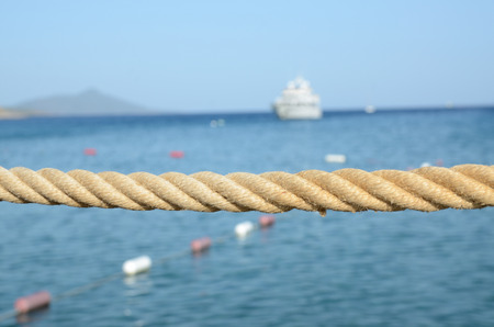 Holiday resort Bagla near Bodrum in Turkey. Rope at platform, behind blue Aegean Sea and ship as background.の写真素材