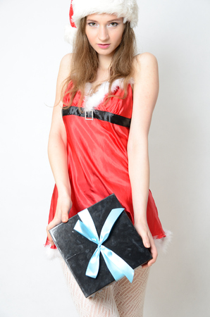 Young female model, Christmas photo session. Twenty years old girl in Santa Claus costume, holding gift box.の写真素材