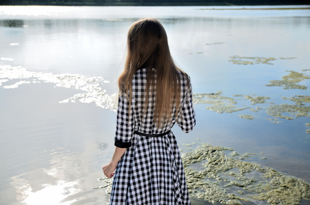 Female model stands in the water. Woman wears dress with black and white pattern.の写真素材