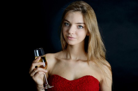 Female model in red dress with glass of champagne in her hand. Evening dress, party.の写真素材