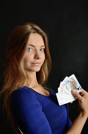 Young woman portrait with black background. Female model holding five poker cards.の写真素材