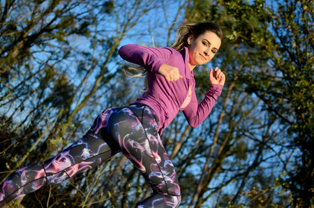 Young girl running in the forest. Blonde female with colorful leggings and purple top. Active runner...