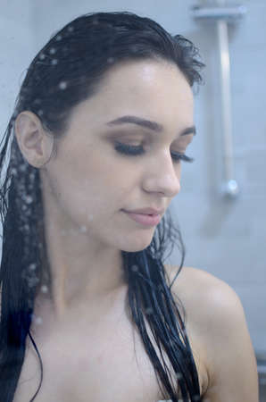 Young woman with wet hairs under shower, visable water drops. Beautiful brunette, Miss Lower Silesia poses at home, indoor photo session.の写真素材