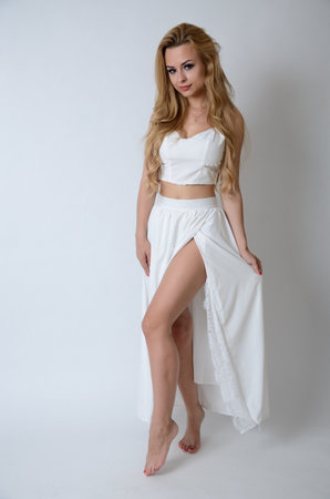 Polish model posing with white top, long white dress with cut, showing her legs.の写真素材