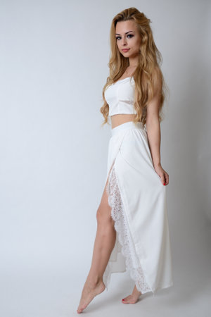 Polish model posing with white top, long white dress with cut, showing her legs.の写真素材