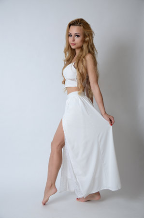 Polish model posing with white top, long white dress with cut, showing her legs.の写真素材