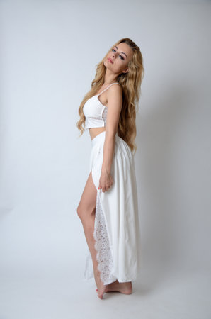 Polish model posing with white top, long white dress with cut, showing her legs.の写真素材