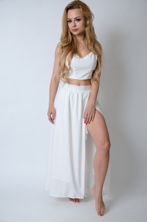 Polish model posing with white top, long white dress with cut, showing her legs.の写真素材