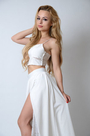 Polish model posing with white top, long white dress with cut, showing her legs.の写真素材
