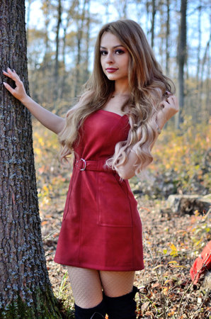 Warm autumn in Poland. Young woman with red dress surrounded by trees. Woman with blonde hair extension.の写真素材