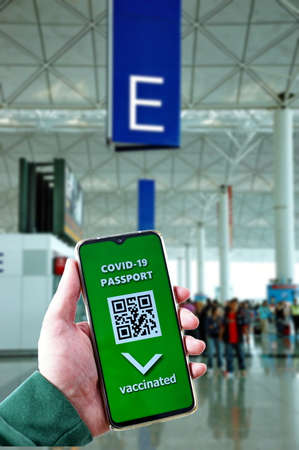 Traveling during SARS-CoV-19 pandemic. Waiting at airport with Covid-19 passport application in mobile phone.の写真素材