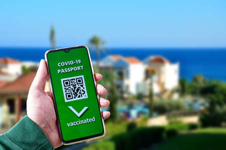Traveling during SARS-CoV-19 pandemic. Holiday resort and Covid-19 passport application in mobile phone.の写真素材