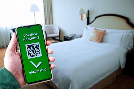 Traveling during SARS-CoV-19 pandemic. Inside hotel room with Covid-19 passport application in mobile phone.の写真素材