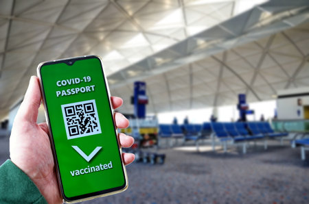 Traveling during SARS-CoV-19 pandemic. Waiting at airport with Covid-19 passport application in mobile phone.の写真素材