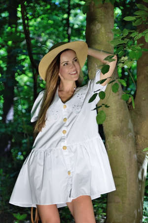 Woman in her 30's posing with white dress in the park. Summer in Poland, green forest.の写真素材