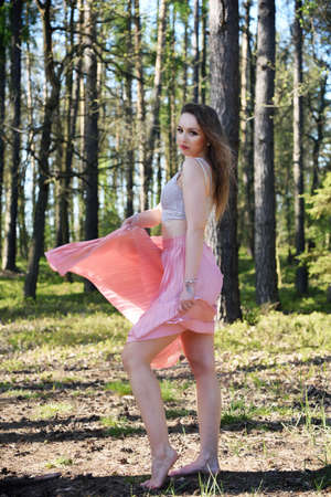 Pretty, young woman, spinning turn with pinky skirt in the forest. Green surroundings during spring in Poland.の写真素材