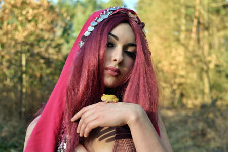 Female model in forest, daytime photo session. Young woman with red hairs, princess with frog.の写真素材