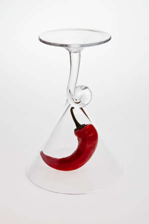 A red chilli pepper under wine glass.の写真素材