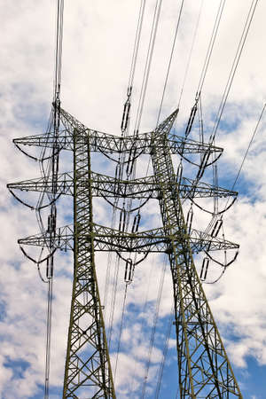 High voltage power line pole over blue sky with white clouds.の写真素材