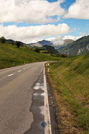 Winding mountain road under cloudy sky in summer.の写真素材