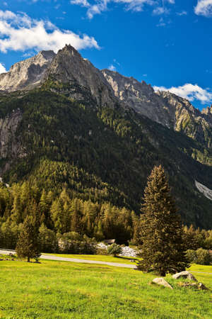 Alpine landscape at summer with high rocky summits over blue sky.の写真素材
