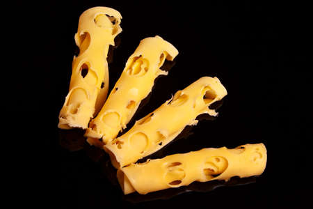Four yellow swiss cheese rolls over black background.の写真素材