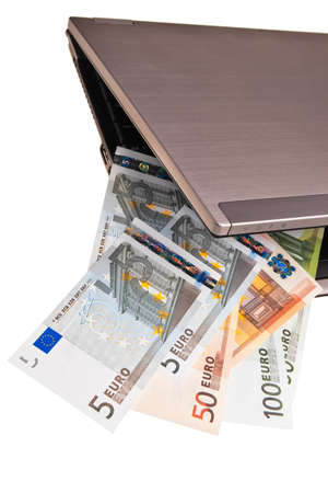 Euro banknotes slipping out of laptop keyboard over white background.の写真素材